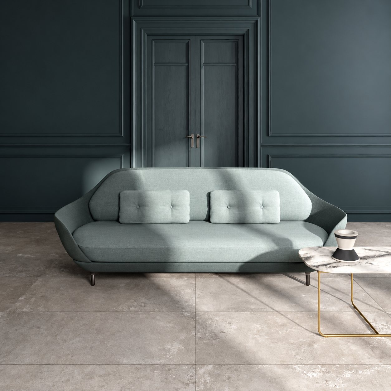 Un canapé design bleu-gris avec deux coussins capitonnés est posé sur un carrelage gris clair devant une porte à double battant et des murs sombres, à côté d'une table basse en marbre au pied doré.