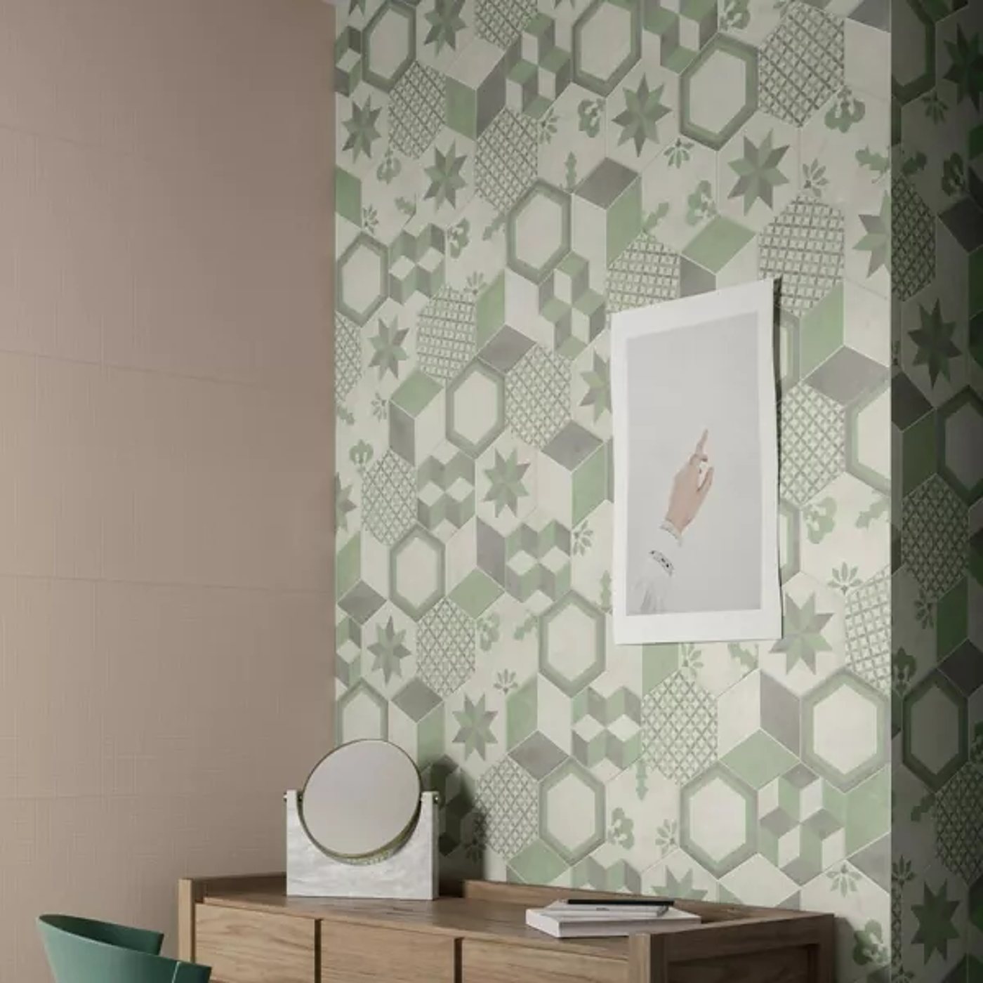 Un mur recouvert de carreaux à motifs géométriques verts et gris, avec une console en bois, un miroir rond et une affiche encadrée.
