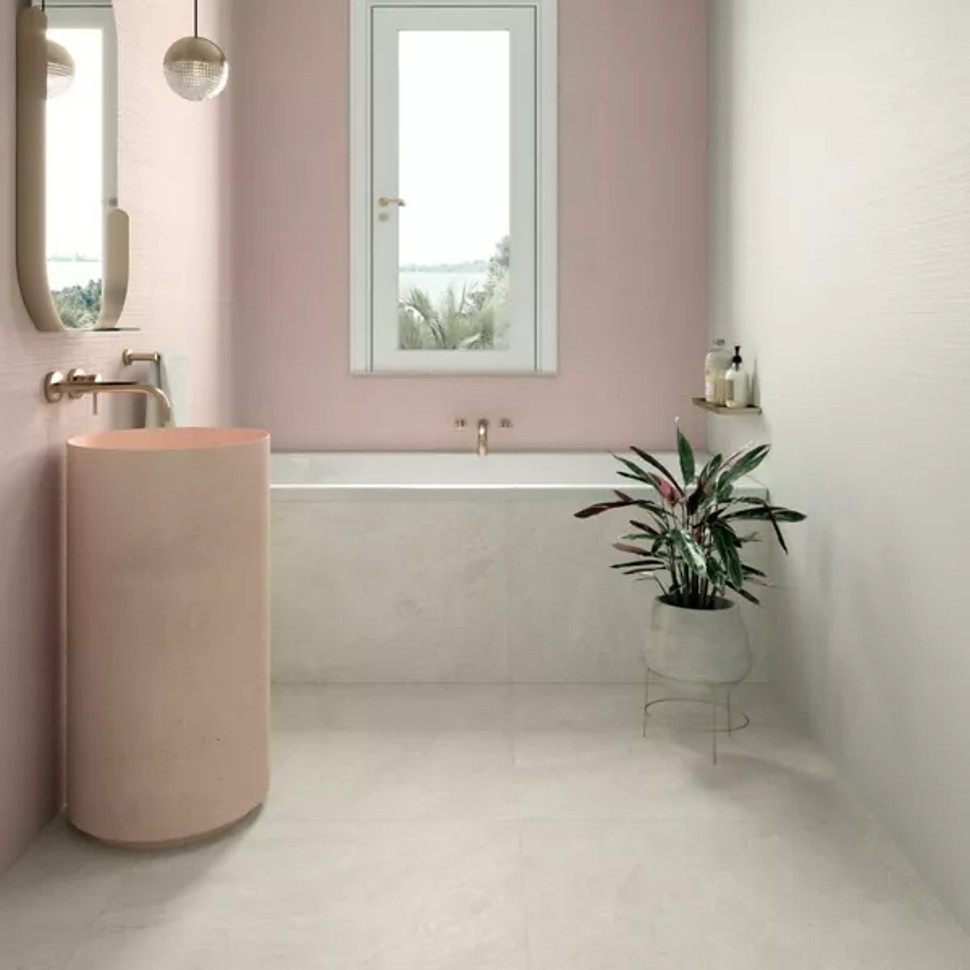 Salle de bain aux murs rose pâle avec une vasque colonne rose, une baignoire encastrée, un carrelage clair au sol et une plante verte.