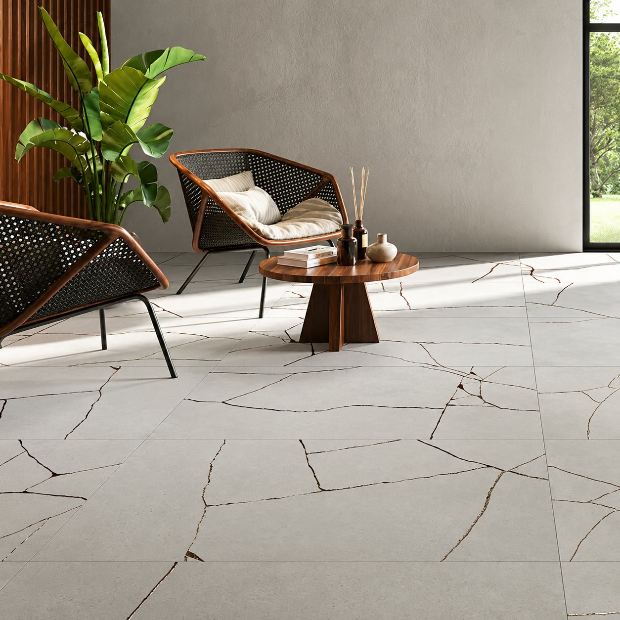 Deux fauteuils en rotin noir et une table basse en bois sur un grand carrelage gris à fines veines noires, près d'une plante verte.